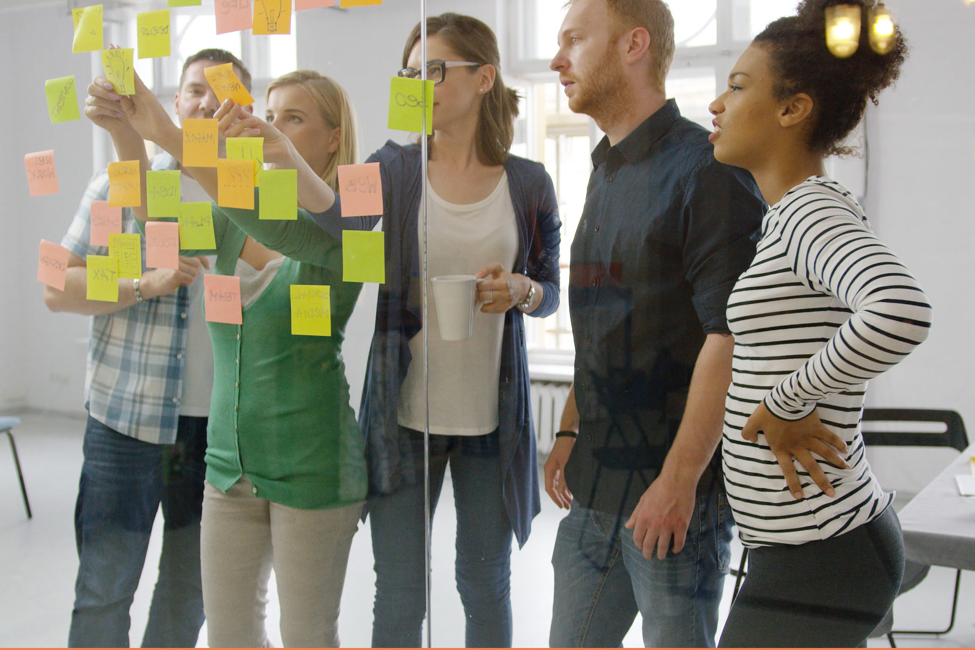 A group of people reviewing lots of ideas on sticky notes stuck to a wall.